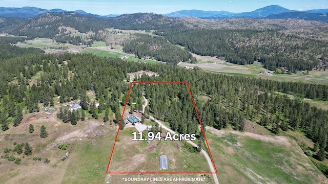 view of property location featuring mountains, a heavily wooded area, and property boundaries highlighted