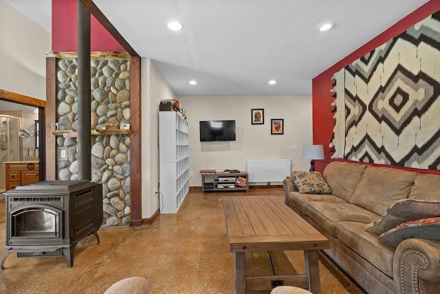 living room with radiator heating unit, recessed lighting, baseboards, a wood stove, and a textured ceiling