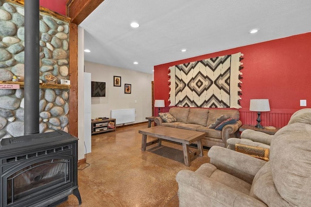 living area with a wood stove, recessed lighting, finished concrete floors, and radiator heating unit