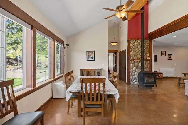 dining room featuring a wood stove, high vaulted ceiling, concrete flooring, a ceiling fan, and recessed lighting