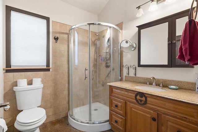 full bathroom with a stall shower, vanity, toilet, and tile walls