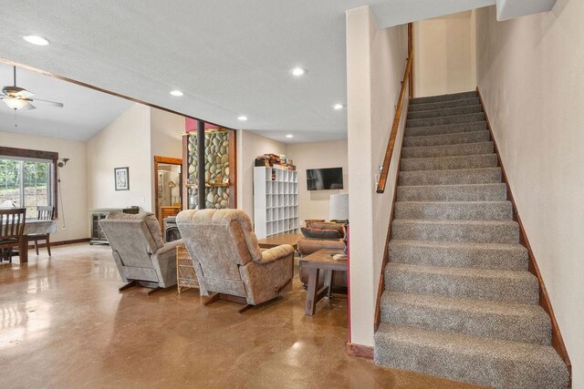 stairs featuring concrete floors, recessed lighting, ceiling fan, and lofted ceiling