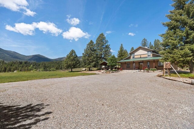 view of front facade with a mountain view, gravel driveway, and a porch