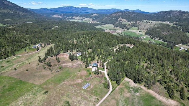aerial view of property and surrounding area featuring a forest and a mountain backdrop