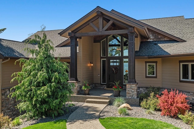 view of exterior entry featuring roof with shingles and stone siding