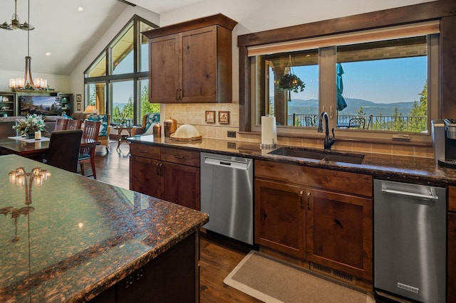 kitchen with stainless steel dishwasher, a sink, tasteful backsplash, dark wood-style flooring, and dark stone countertops