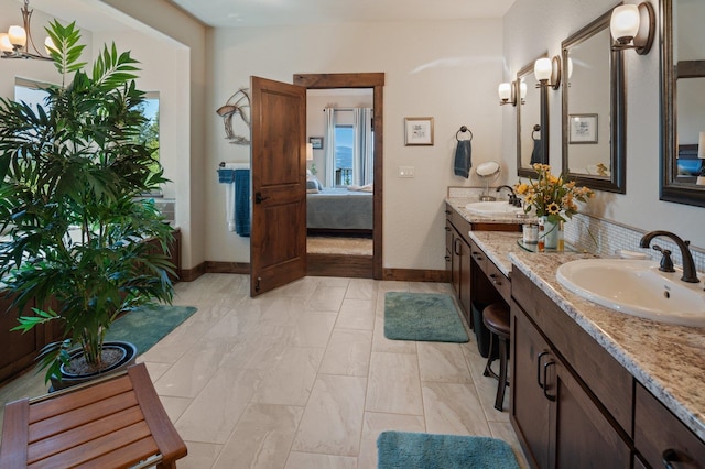 bathroom featuring double vanity, ensuite bathroom, baseboards, and a chandelier