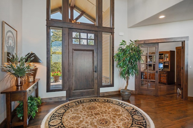 foyer entrance featuring wood finished floors, lofted ceiling, and baseboards