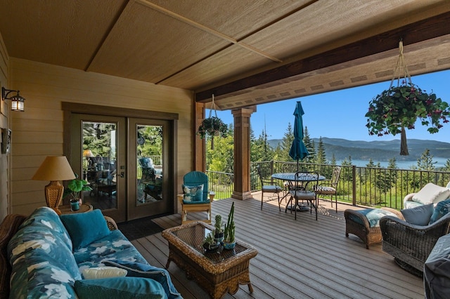 wooden terrace with french doors, a mountain view, outdoor dining space, and an outdoor living space