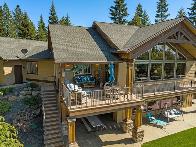 rear view of property with a shingled roof, a patio area, stairs, and a deck