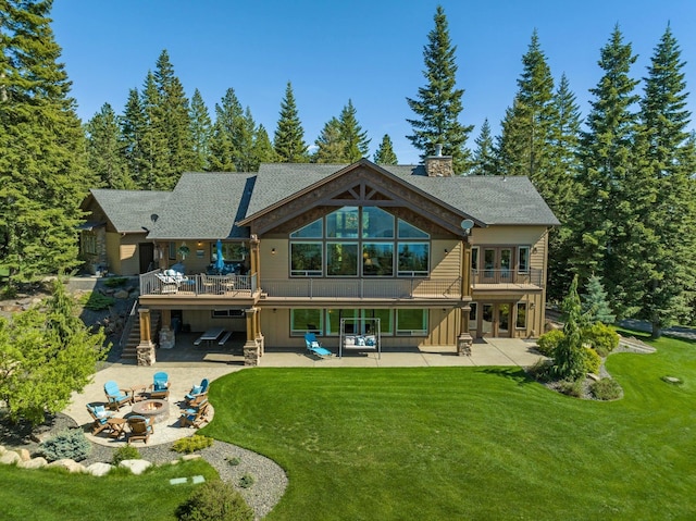 rear view of property featuring a fire pit, stairs, a patio area, and a lawn