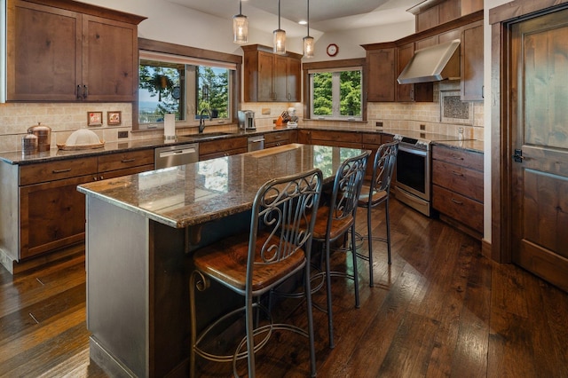 kitchen with stainless steel appliances, exhaust hood, dark wood-style flooring, and tasteful backsplash