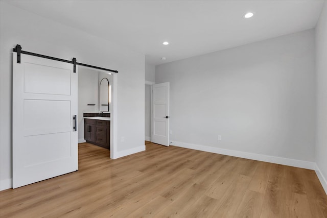 7025 E Beverly Ave, Spokane Valley, WA 99212 - unfurnished bedroom with a barn door, light wood-style flooring, baseboards, and recessed lighting