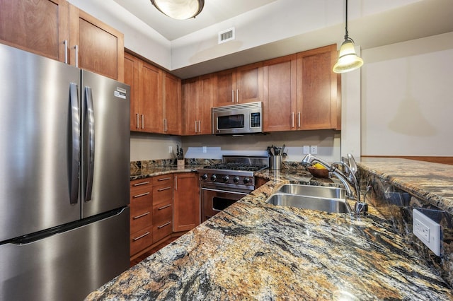 316 S 10th Pl, Coeur D Alene, ID 83814 - kitchen with stainless steel appliances, a sink, dark stone countertops, decorative light fixtures, and brown cabinets