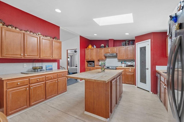 91 Moonlight Ln, Newport, WA 99156 - kitchen featuring a skylight, light wood-style flooring, tasteful backsplash, under cabinet range hood, and recessed lighting