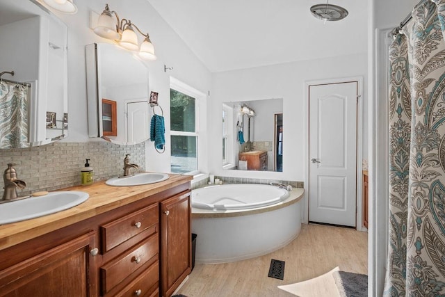 91 Moonlight Ln, Newport, WA 99156 - full bathroom featuring wood finished floors, tasteful backsplash, a bath, double vanity, and lofted ceiling