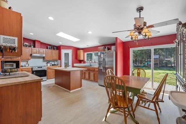 91 Moonlight Ln, Newport, WA 99156 - kitchen with stainless steel appliances, under cabinet range hood, light wood-type flooring, a center island, and vaulted ceiling