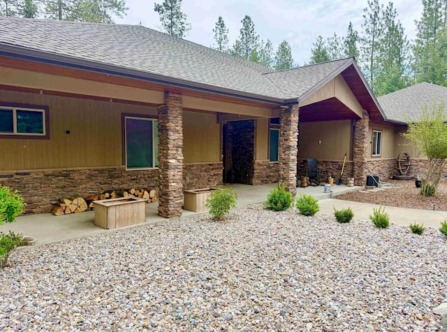 315 Palmer Ln, Chewelah, WA 99109 - back of house with stone siding, roof with shingles, and a patio area