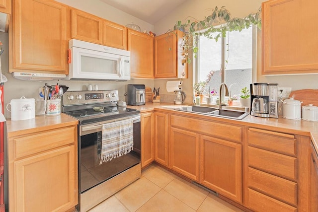 kitchen featuring white microwave, stainless steel electric range, a sink, light countertops, and light tile patterned floors