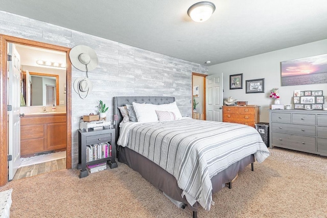 bedroom with ensuite bathroom, a sink, and light colored carpet