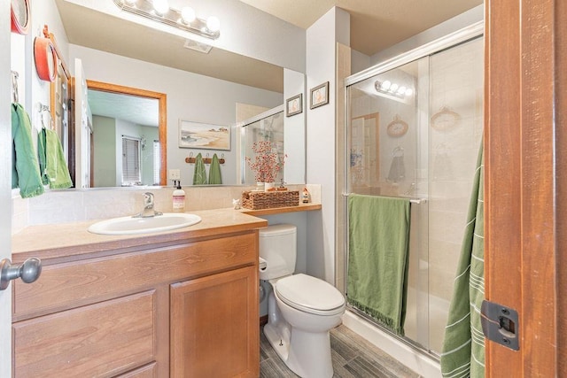 bathroom with toilet, a stall shower, and vanity