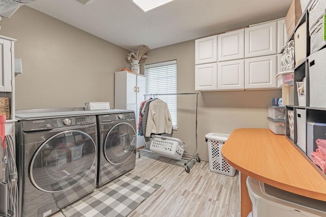 laundry room with cabinet space, washer and dryer, and light wood-type flooring