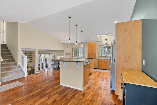 7007 N Tucannon Ct, Spokane, WA 99208 - kitchen featuring a breakfast bar, light wood-style floors, stainless steel appliances, lofted ceiling, and a chandelier