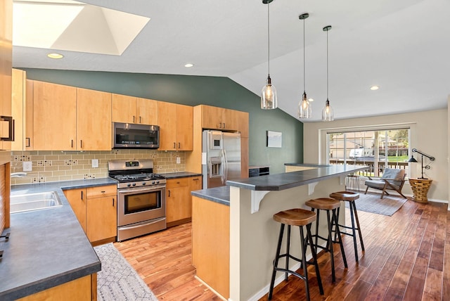 7007 N Tucannon Ct, Spokane, WA 99208 - kitchen with appliances with stainless steel finishes, light wood-type flooring, lofted ceiling, a breakfast bar area, and dark countertops