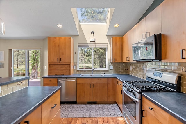 7007 N Tucannon Ct, Spokane, WA 99208 - kitchen with stainless steel appliances, dark countertops, decorative backsplash, a skylight, and light wood finished floors