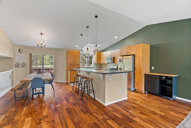 7007 N Tucannon Ct, Spokane, WA 99208 - kitchen featuring appliances with stainless steel finishes, a chandelier, a kitchen bar, dark wood finished floors, and lofted ceiling