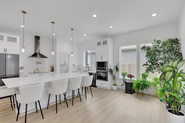 kitchen with wall chimney range hood, appliances with stainless steel finishes, decorative backsplash, light countertops, and recessed lighting