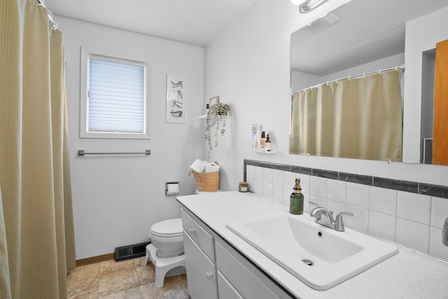 bathroom featuring decorative backsplash, baseboards, vanity, and toilet