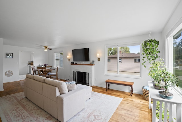 living area featuring a ceiling fan, wood finished floors, a fireplace, and baseboards