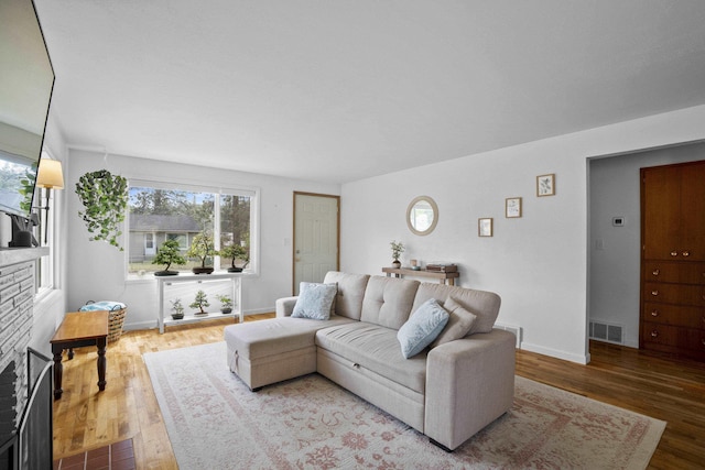 living area featuring wood finished floors, baseboards, and a brick fireplace