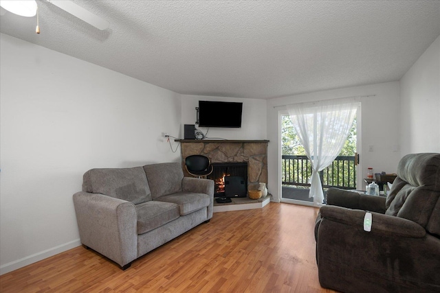 6019 E 6th Ave Unit L-201, Spokane, WA 99212 - living room featuring light wood-style flooring, a ceiling fan, a fireplace, a textured ceiling, and baseboards