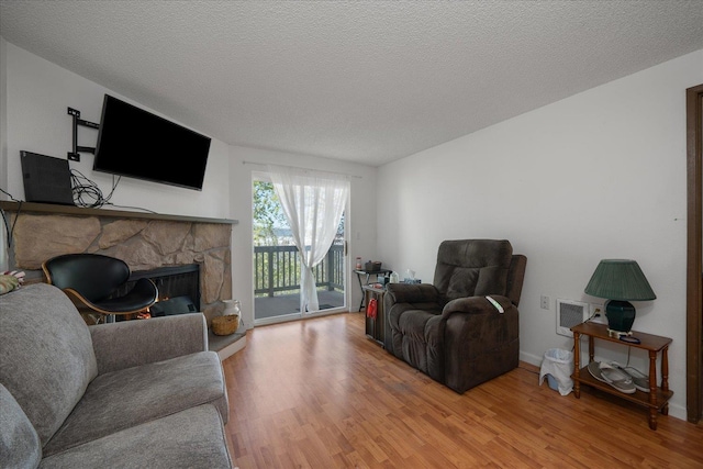6019 E 6th Ave Unit L-201, Spokane, WA 99212 - living room with light wood-style flooring, a stone fireplace, and a textured ceiling