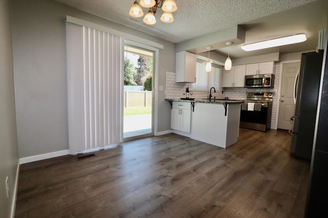 13703 E 31st Ave, Spokane Valley, WA 99216 - kitchen featuring appliances with stainless steel finishes, a chandelier, backsplash, a breakfast bar area, and a peninsula