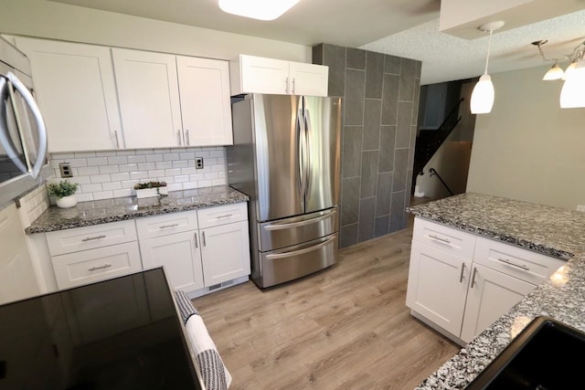 13703 E 31st Ave, Spokane Valley, WA 99216 - kitchen featuring freestanding refrigerator, white cabinets, light wood-type flooring, dark stone counters, and decorative light fixtures
