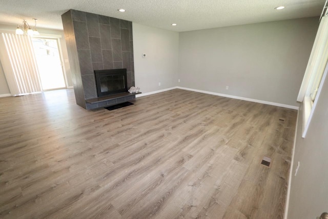 13703 E 31st Ave, Spokane Valley, WA 99216 - unfurnished living room featuring wood finished floors, a textured ceiling, baseboards, recessed lighting, and a tile fireplace