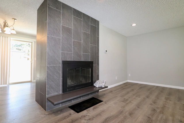 13703 E 31st Ave, Spokane Valley, WA 99216 - unfurnished living room featuring a textured ceiling, wood finished floors, a fireplace, a chandelier, and baseboards