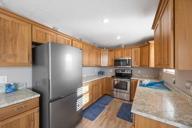 23605 E Beach Ln, Newman Lake, WA 99025 - kitchen featuring stainless steel appliances, light wood-style flooring, light countertops, brown cabinetry, and recessed lighting