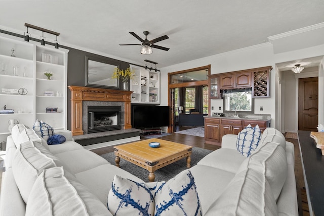 living area featuring dark wood-type flooring, ornamental molding, ceiling fan, and a fireplace
