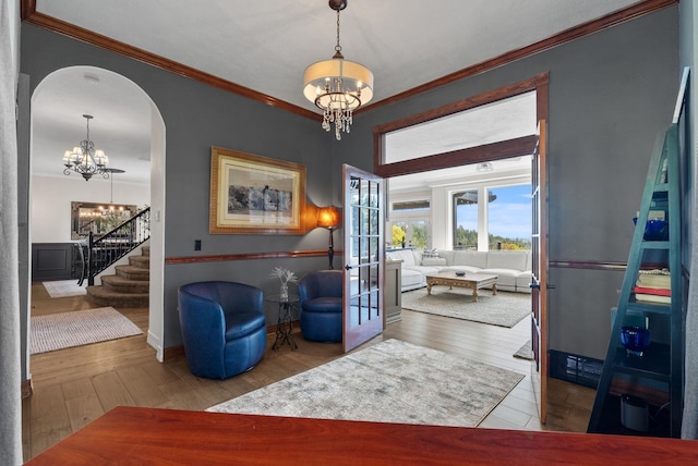 sitting room with a chandelier, crown molding, arched walkways, hardwood / wood-style floors, and stairway