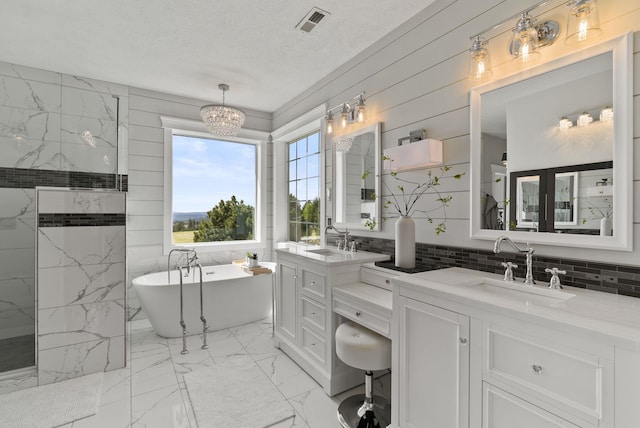 bathroom with marble look tile flooring, a freestanding bath, vanity, a chandelier, and a textured ceiling