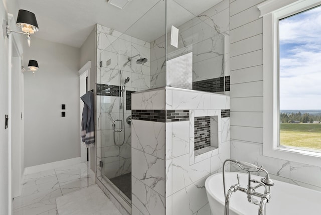full bath featuring healthy amount of natural light, marble finish floors, a marble finish shower, and a freestanding tub