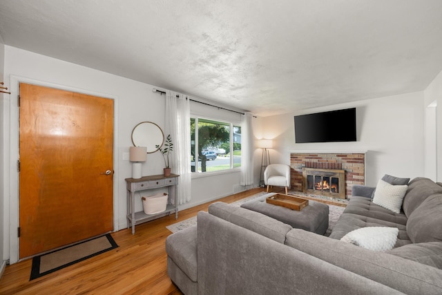 living room featuring light wood finished floors and a brick fireplace