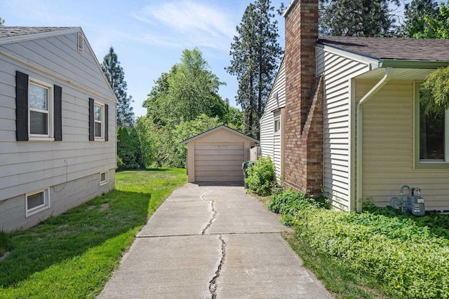 view of property exterior featuring an outbuilding, a chimney, a detached garage, a lawn, and a shingled roof