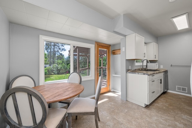 kitchen featuring a sink, white cabinetry, baseboards, and light floors