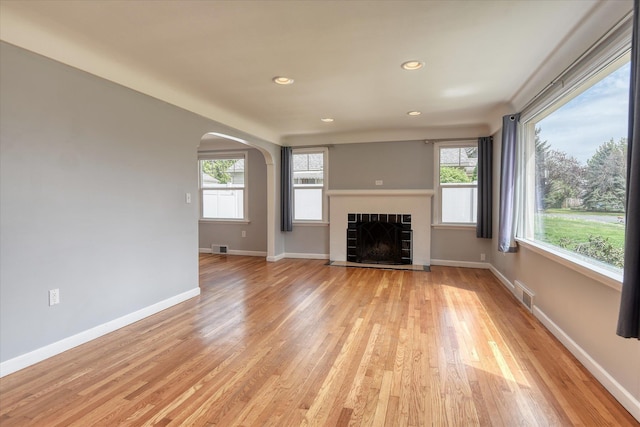 2410 W Upton Ave, Spokane, WA 99205 - unfurnished living room with arched walkways, a tiled fireplace, light wood finished floors, baseboards, and recessed lighting