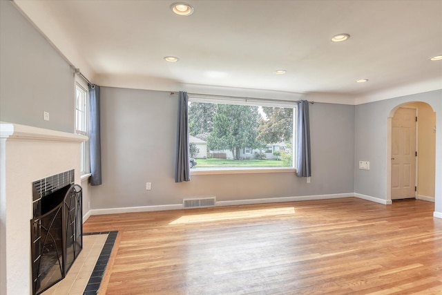 2410 W Upton Ave, Spokane, WA 99205 - unfurnished living room featuring a tiled fireplace, arched walkways, light wood finished floors, recessed lighting, and baseboards